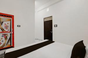 a bedroom with a white bed and a black door at SPOT ON Galaxy Hotal in Prayagraj