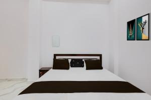 a bedroom with a white bed with black pillows at SPOT ON Galaxy Hotal in Prayagraj