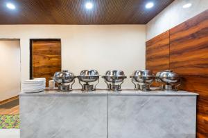 a row of silver bowls on a counter in a kitchen at Treebo Himalayan Homestay in Pune