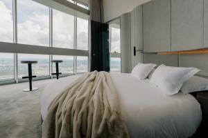 a bedroom with a large white bed with large windows at Vilnius TV Tower Apartments DEBESYS in Vilnius