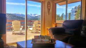 a living room with a view of a balcony at Rocky Mountain Panorama Cabin in Estes Park
