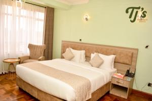 a hotel room with a large bed and a chair at TJ's Boutique Hotel in Eldoret