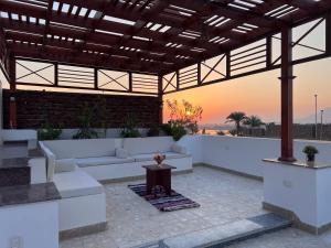 an outdoor patio with a couch and a table at Spacious Luxury Nile-View Apartment on Upper Floor with Rooftop, Jacuzzi & BBQ ,Steps from Hilton Hotel in Luxor