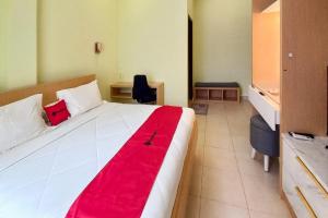 a bedroom with a large white bed with a red blanket at RedDoorz Syariah at UIN Suska GuestHouse in Pekanbaru +19 photos