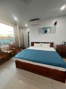 a bedroom with a large bed with a blue blanket at Manh Vuong Buotique Hotel in Cat Ba