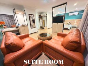 a living room with two leather couches and a tv at Heritage Hotel in Tawau