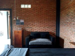 a room with a couch against a brick wall at Beachfront Guest House Pacitan in Tamperan