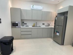 a kitchen with white cabinets and a refrigerator at شقة ياسمين الفندقية in Medina