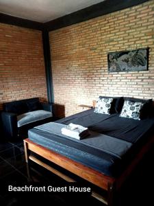 a bedroom with a bed and a brick wall at Beachfront Guest House Pacitan in Tamperan