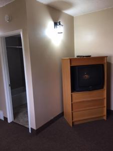 a living room with a tv and a dresser with a television at Nights Inn Motel in Thunder Bay