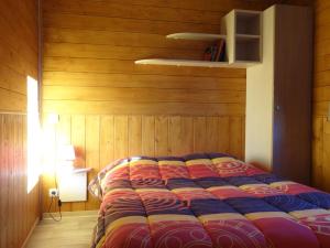 ein Bett in einem Zimmer mit einer Holzwand in der Unterkunft Chalets du Lac in Arcizans-Avant + 21 Fotos