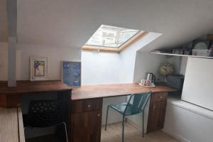 a kitchen with a desk with a chair and a window at Chambre de charme dans maison coloniale in Noumea