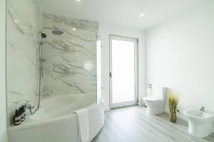 a white bathroom with a tub and a sink at Seaview Villa with Heated Private Pool in Bretanha