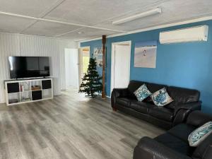 a living room with a black couch and a christmas tree at Cervantes Beach Shack in Cervantes