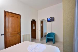 a room with a bed and a door and a blue chair at Hotel Garden Bocca di Magra in Bocca di Magra