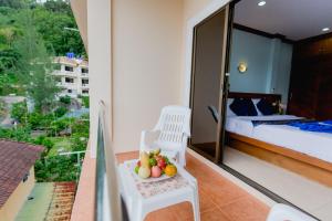 a room with a balcony with a bed and a bowl of fruit at RK Guesthouse in Patong Beach