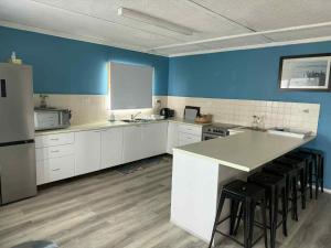 a kitchen with white cabinets and a blue wall at Cervantes Beach Shack in Cervantes