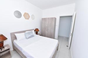 a white bedroom with a bed and a sliding glass door at Hyacinth Golf& Sea in Grand-Baie
