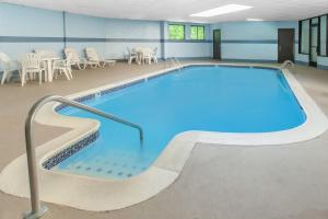 a swimming pool with blue water in a building at Days Inn & Suites by Wyndham Madison Heights MI in Madison Heights