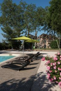 Ouveillan的住宿－Le Relais De Pigasse，一组躺椅和一把遮阳伞,位于游泳池旁