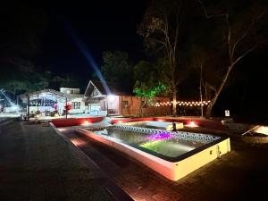 a swimming pool with lights in a yard at night at The Cool Cottage, Pool Extra, at gaya3farms in Palakkad