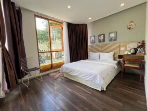 a bedroom with a bed and a desk and a window at Vindy House in Da Lat +143 photos