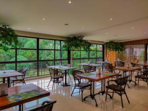 a restaurant with tables and chairs and large windows at Holiday Inn & Suites Batangas LimaPark by IHG in Batangas City