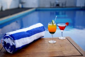 two cocktails on a table next to a swimming pool at BigStay Apart Hotel in Tada