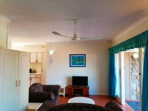 a living room with a ceiling fan and a tv at All the Tides - Rip Tide in Margate