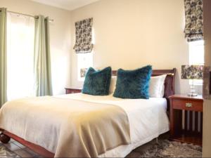 a bedroom with a large bed with blue pillows at Meander Stay Clarens in Clarens