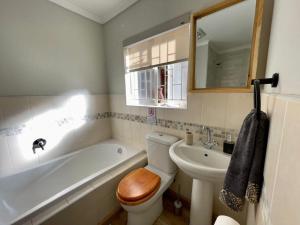 a bathroom with a toilet and a sink and a tub at Meander Stay Clarens in Clarens