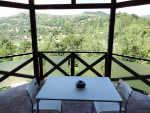 - une table et des chaises blanches dans une chambre avec vue dans l'établissement Pensiunea Cabana Veverita Valea Doftanei, à Trăisteni