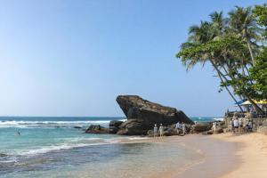 a group of people standing on a beach near the ocean at Gatch Villa in Unawatuna