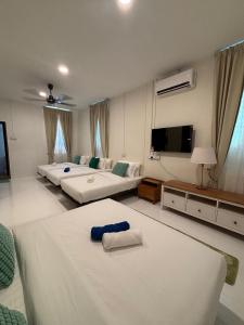 a large living room with two beds and a flat screen tv at Sunset Beach Retreat & Beach Bistro in Batu Ferringhi