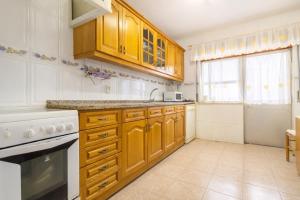 Eine Küche mit Holzschränken und weißen Geräten in der Unterkunft Stay in Corroios Near Lisbon and 15 Min from the Beach - Casa Acolhedora em Corroios Perto de Lisboa e da Praia in Corroios