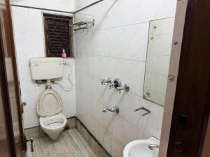 a bathroom with a toilet and a shower with a mirror at Ozzy Rooms in Kolkata