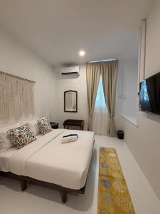 a bedroom with a large white bed and a flat screen tv at Sunset Beach Retreat & Beach Bistro in Batu Ferringhi