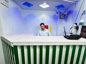a man standing behind a table with a laptop at Hotel Shopno Abasik in Dhaka