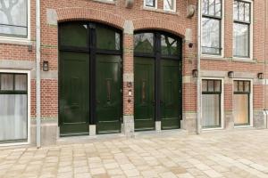 two green doors on the side of a brick building at Hotel Middelland Rotterdam in Rotterdam