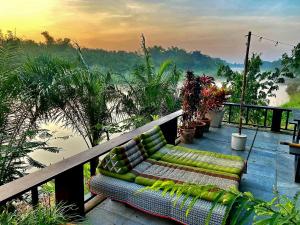 a couch on a balcony with a view of a river at Baantidnam in Ban Thung Tho