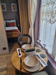 a wooden table with plates and wine glasses on it at Villa Seven Petit Studio coin kitchenette in Dunkerque