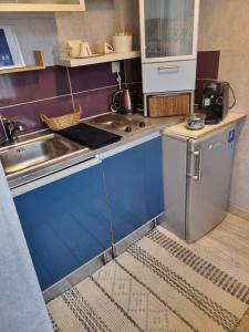 a small kitchen with blue cabinets and a sink at Villa Seven Petit Studio coin kitchenette in Dunkerque