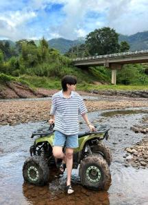 a man standing on a four wheeler in a river at สะปันไลฟ์ in Ban Huai Ti