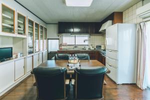 a kitchen with a table and chairs and a refrigerator at keganiya 一棟貸し北九州空港近くの和風宿 in Yukuhashi