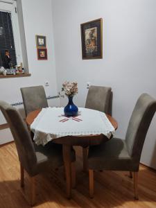 a dining room table with four chairs and a vase on it at Signorina in Smederevo