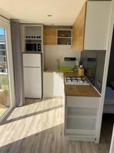 a kitchen with a white refrigerator and a stove at Camping de la Mer in Camiers