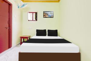 a white and black bed in a room at Hotel O V Guest In in Guntūr