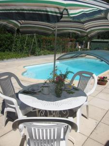 una mesa con sillas y una sombrilla junto a la piscina en Au Verger B&B, en Sospel