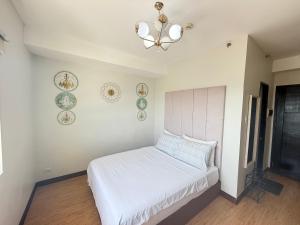 a bedroom with a bed with a chandelier and plates on the wall at Compact Studio Unit At Mesaverte Residences in Pontud +5 photos