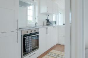 a white kitchen with white cabinets and a fireplace at Gullbrannagården in Halmstad